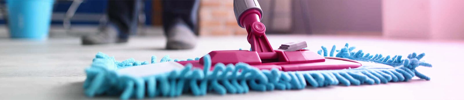 Mop cleaning floor with blue microfiber pad and pink handle, representing professional cleaning services for move-in and move-out by Colombian Cleaning.